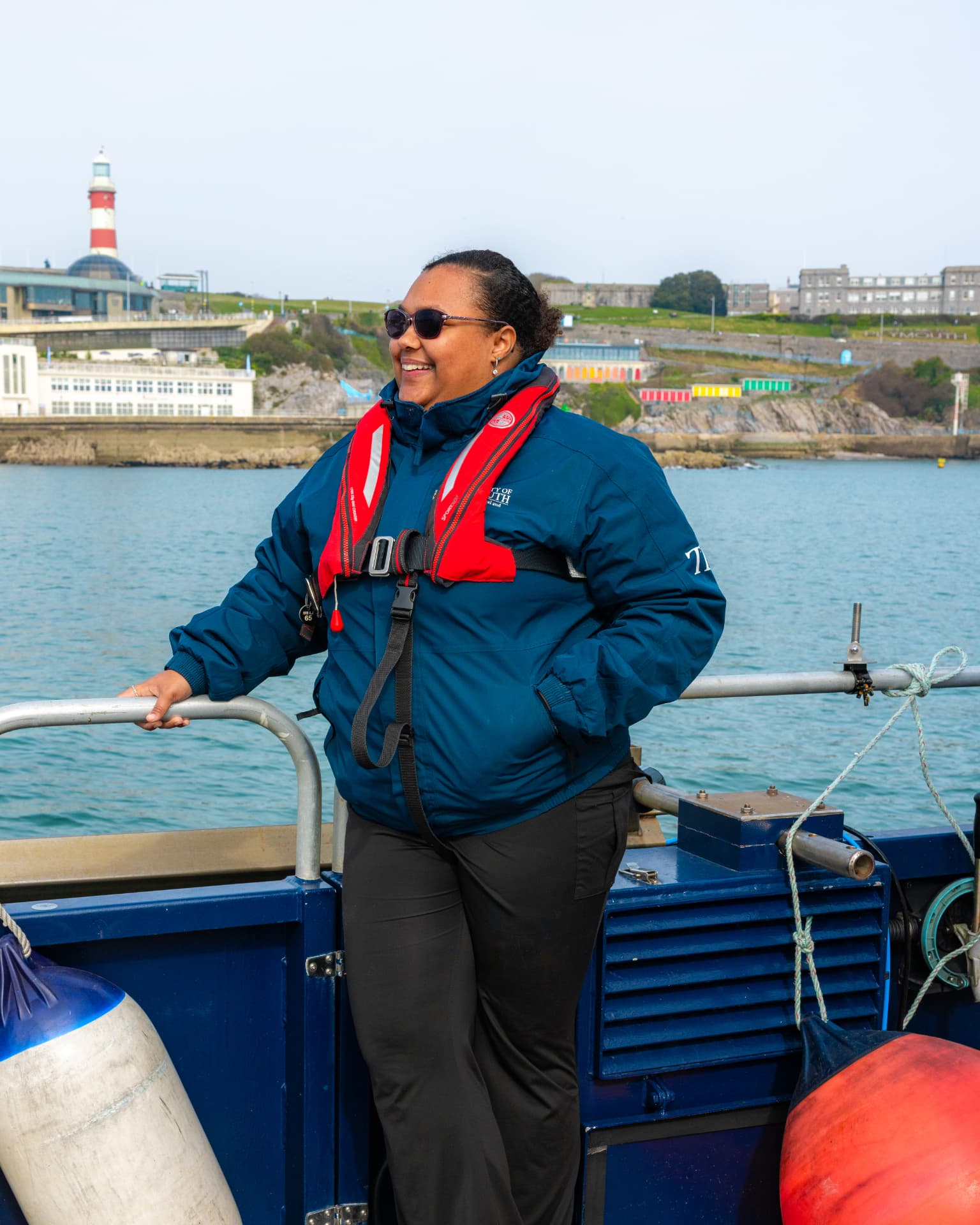 Tsian smiling on a boat, wearing a navy jacket and red life jacket.