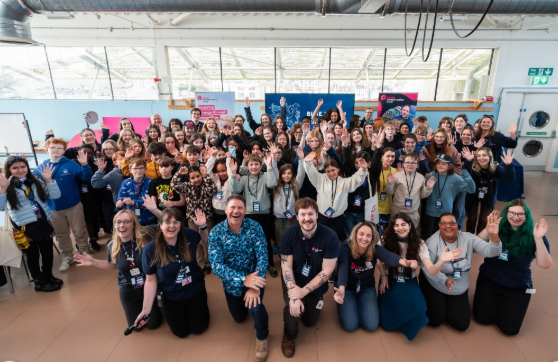 A large group smiling and waving for a group photograph.