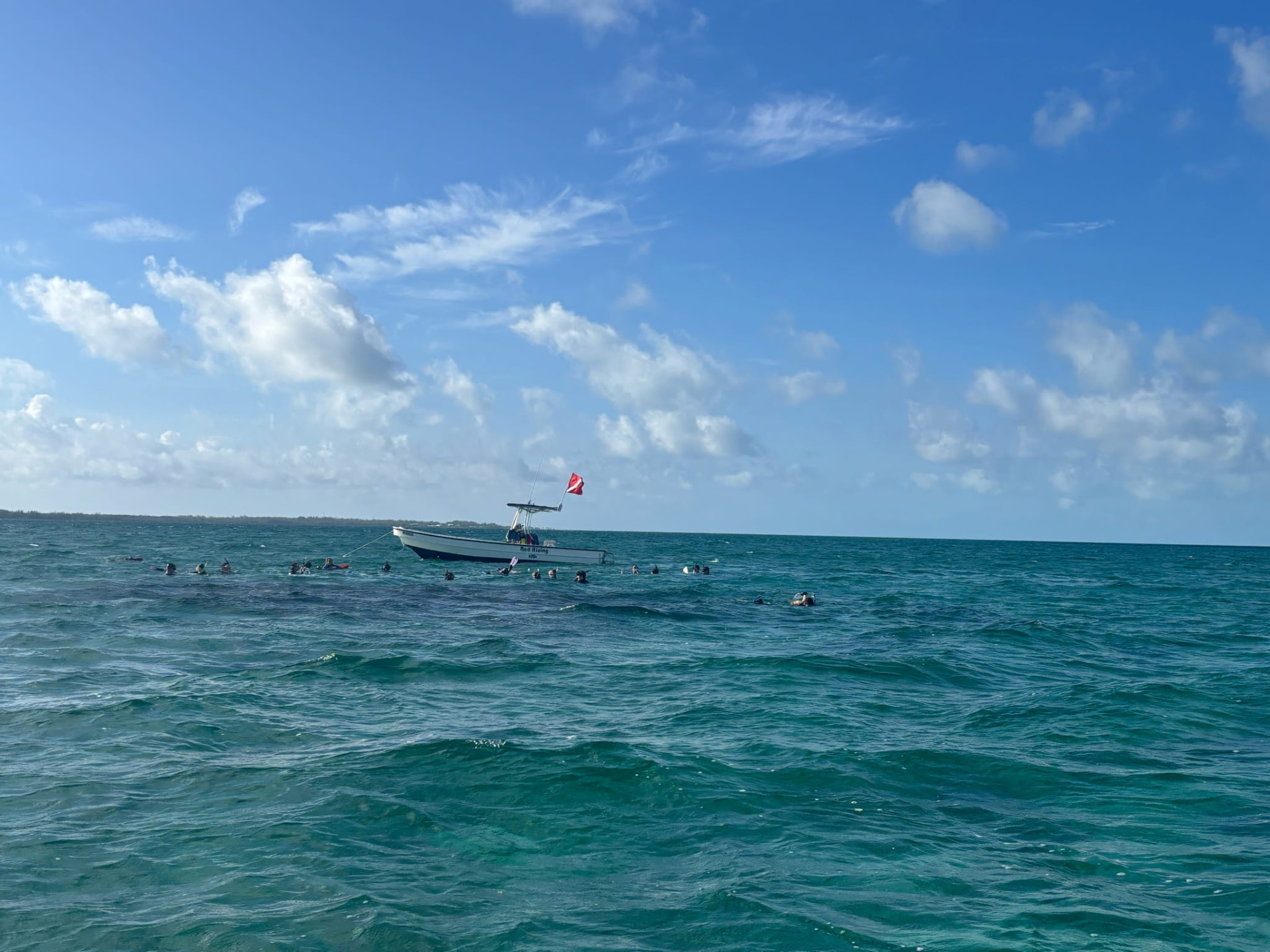 Swimmers near a small boat in open turquoise water